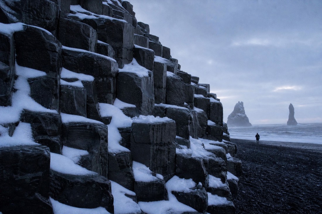 Hexagonal basalt columns at Reynisfjara with snow caught in the fractures, flat overcast light