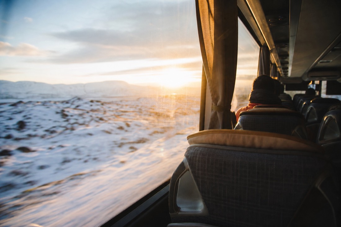 Golden low sun through a coach window onto empty seats, snowy landscape sliding past outside