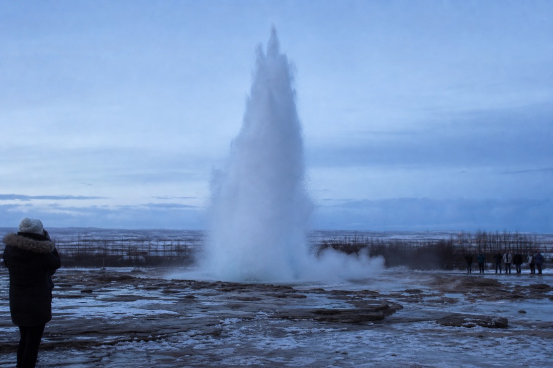 Strokkur geyser erupting against a cold blue winter sky on a Golden Circle day tour