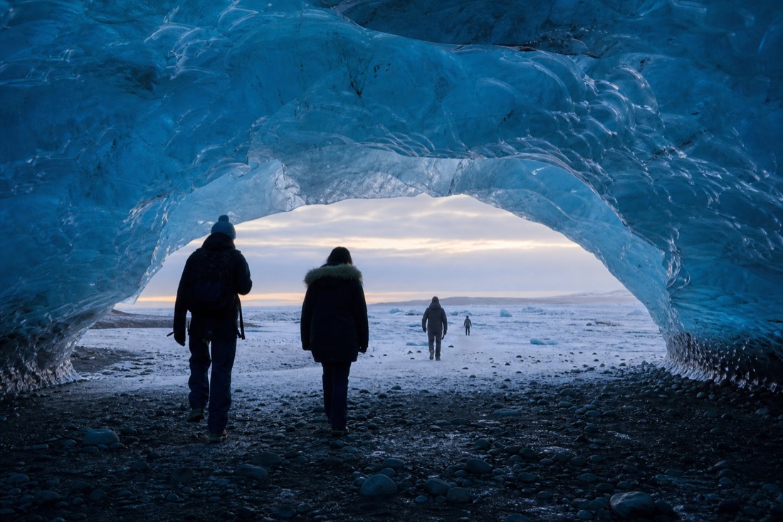 A small group standing inside a natural blue ice cave near Jökulsárlón glacier lagoon