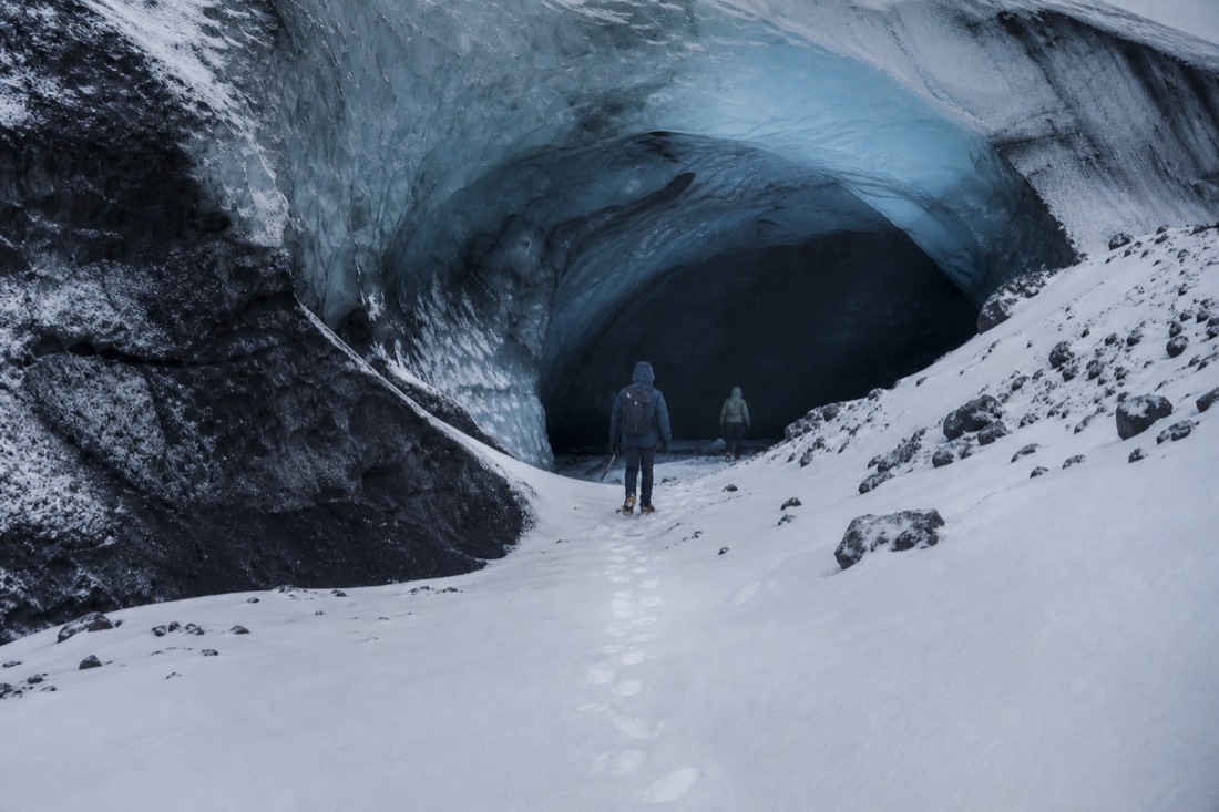 Crampon tracks leading into a natural blue ice cave entrance on Vatnajökull