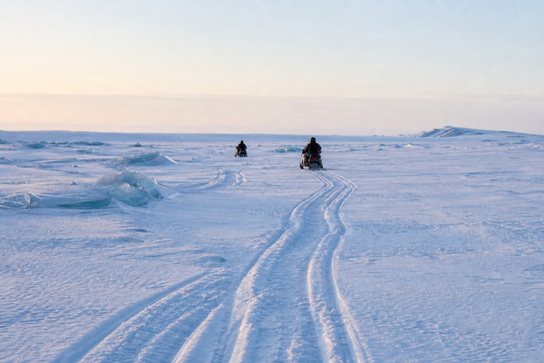 Snowmobile tracks across the flat white surface of Langjokull ice cap, no depth in the light